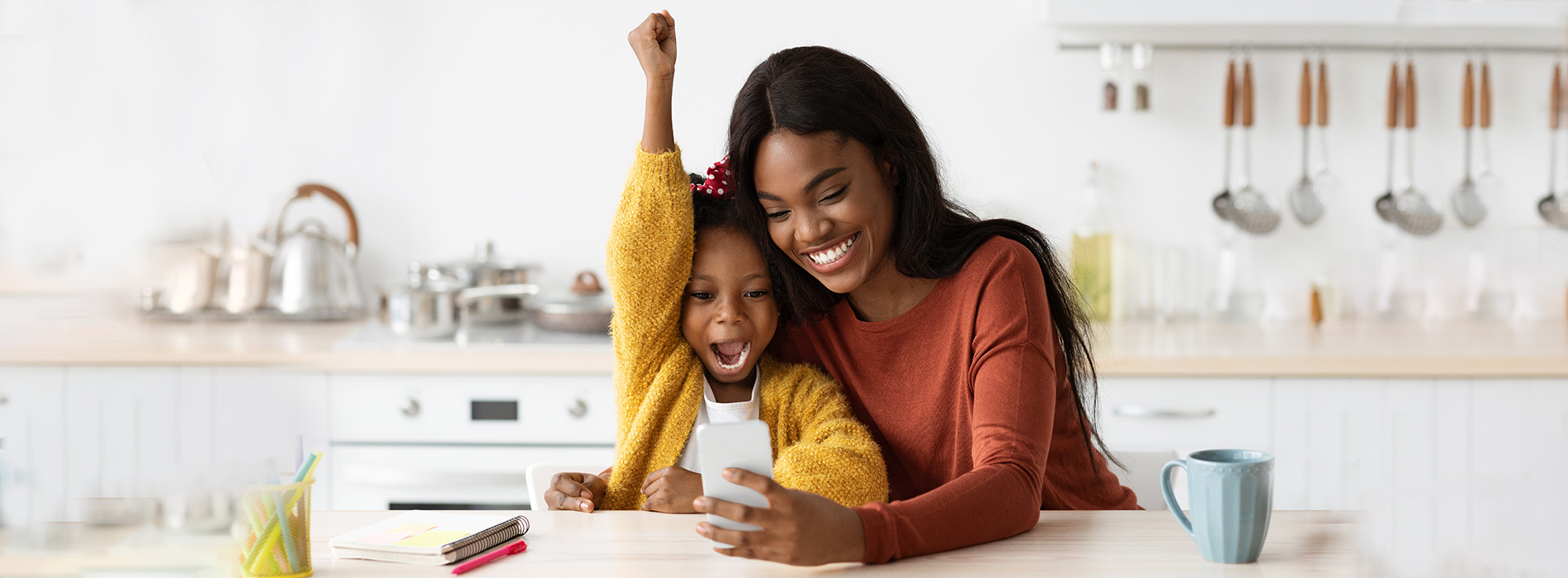 A woman and child sitting at a kitchen counter with a warm, domestic atmosphere.