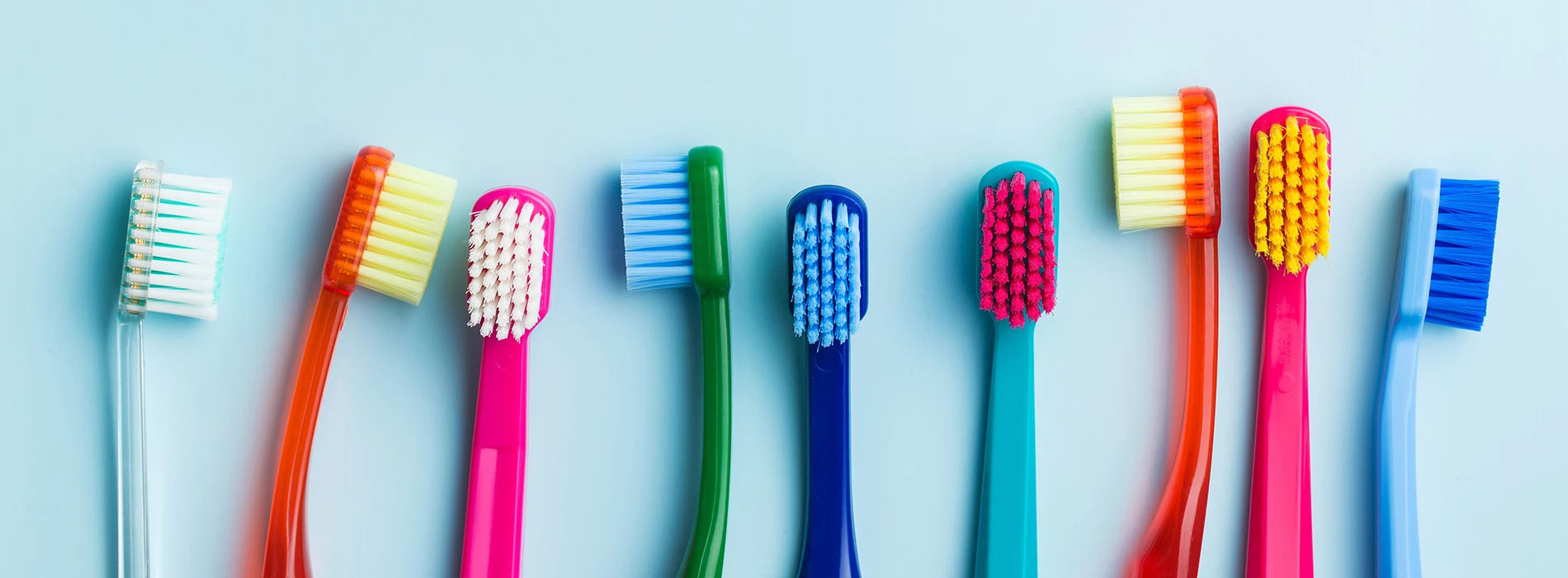 The image shows a row of colorful toothbrushes with different colored bristles.