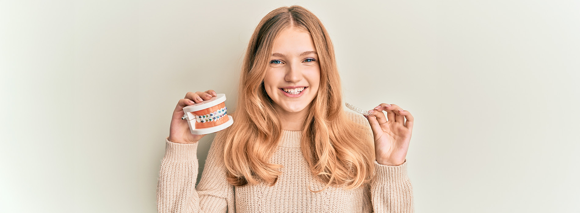 A young woman poses with a cup of coffee, smiling and holding the cup in her hand.