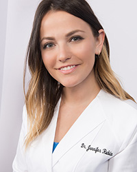 A woman in a white lab coat, smiling and posing for the camera.